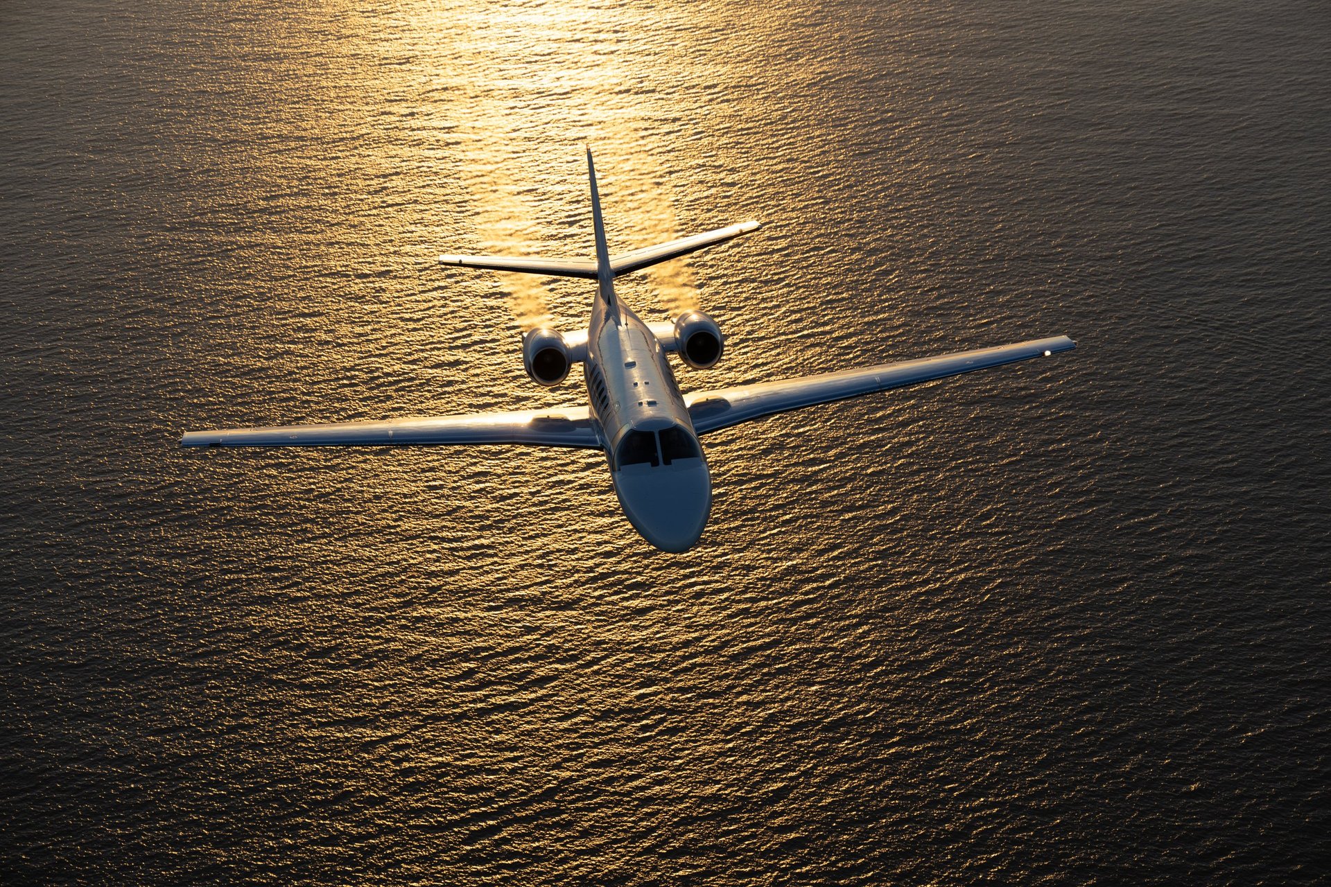 Business jet in beautiful light sunset light, over the Pacific Ocean
